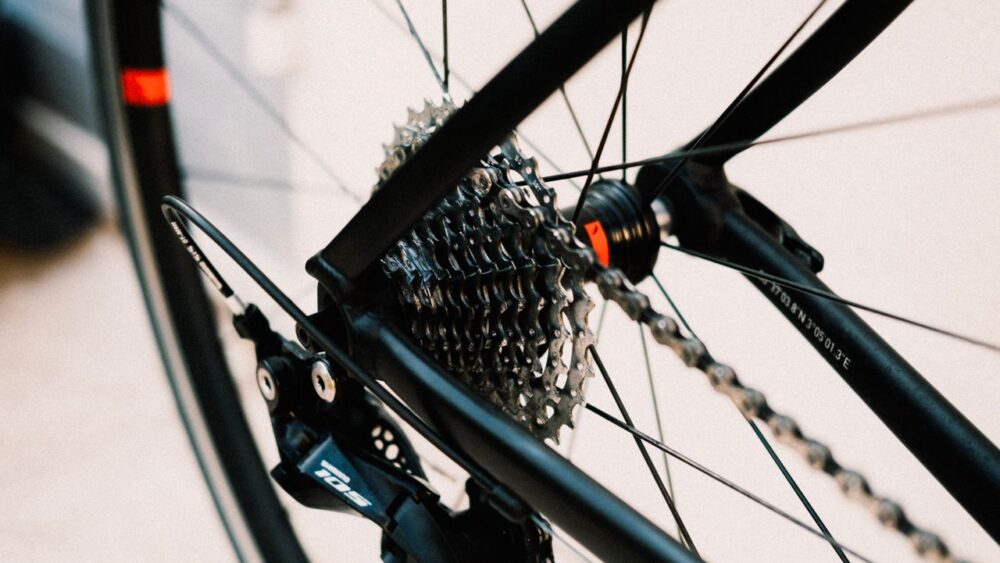 A close-up, shallow-depth-of-field photograph of a bicycle's rear wheel hub, focusing on a multi-speed cassette cog set, a Shimano 105 rear derailleur, and a clean chain.