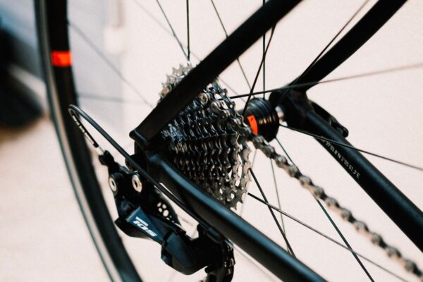 A close-up, shallow-depth-of-field photograph of a bicycle's rear wheel hub, focusing on a multi-speed cassette cog set, a Shimano 105 rear derailleur, and a clean chain.
